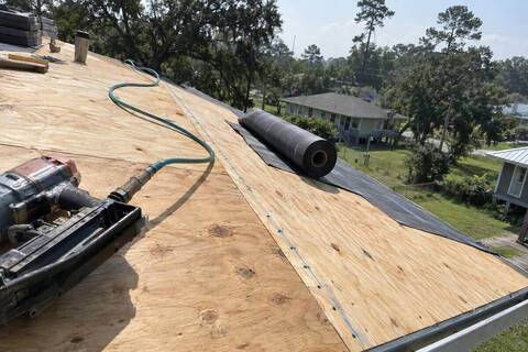 Roof decking panels with a row of nails along a chalk line and underlayment rolled out beside them