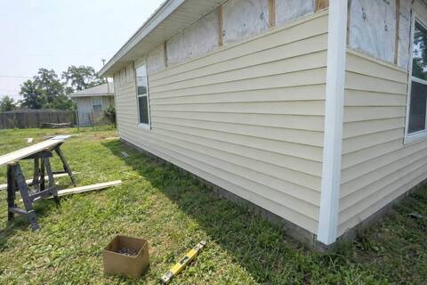 Vinyl lap siding panels meeting a corner post on a small frame house